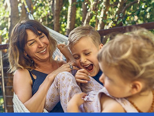 Mother enjoying swinging in a hammock with her son and daughter